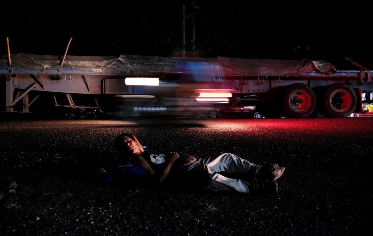 Un hombre, perteneciente a una caravana de migrantes de El Salvador en ruta a los Estados Unidos, descansa en la carretera de Ciudad Tecún, Guatemala.