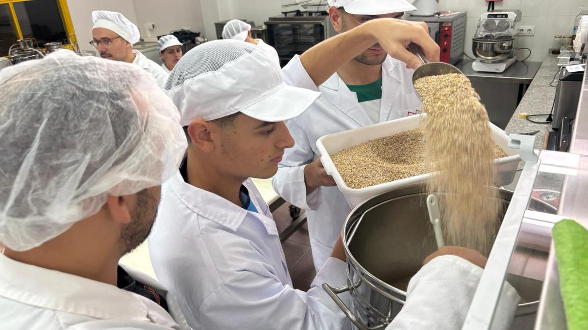 Varios alumnos del instituto San José de Badajoz echan la malta en agua caliente para hacer cerveza artesana.