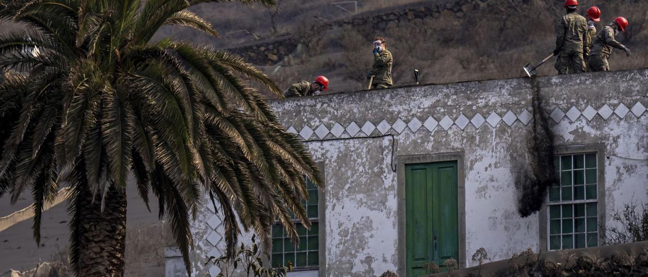 Militares retiran ceniza del tejado de una casa en la zona afectada por la erupción del volcán en La Palma.