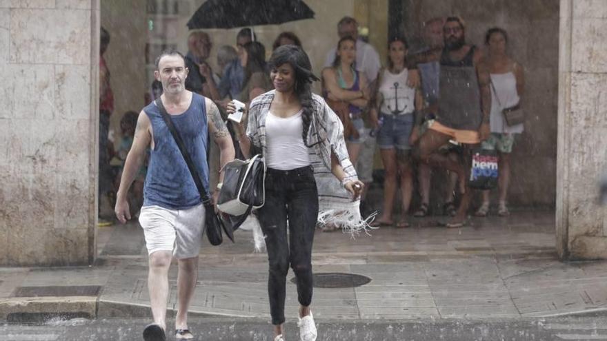 Un hombre y una mujer cruzan Jaume III bajo la lluvia.