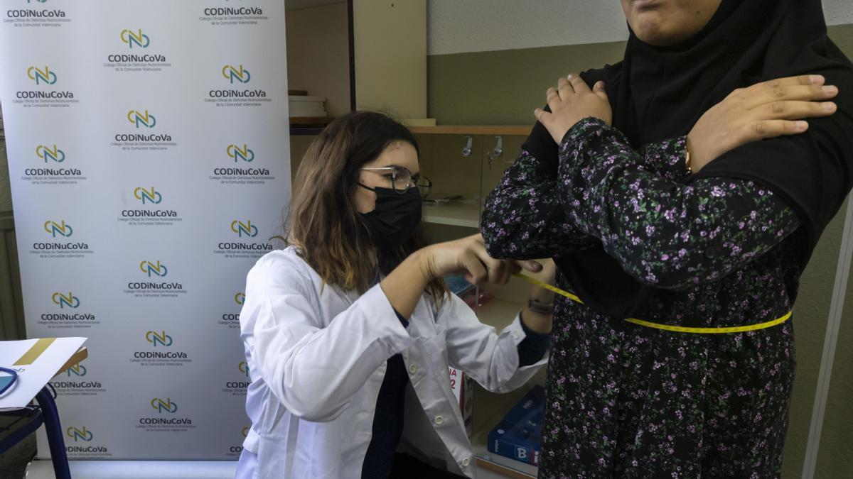 Ruth García, del colegio de Nutricionistas de Valencia, midiendo la cintura de una de las escolares que participa en el estudio. colegio Magisterio Español