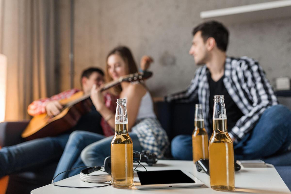 Tres jóvenes bebiendo cerveza sentados en el sofá de un apartamento