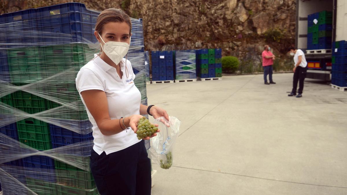 Una trabadora de Mar de Frades muestra un racimo de uva albariña a las puertas de la bodega