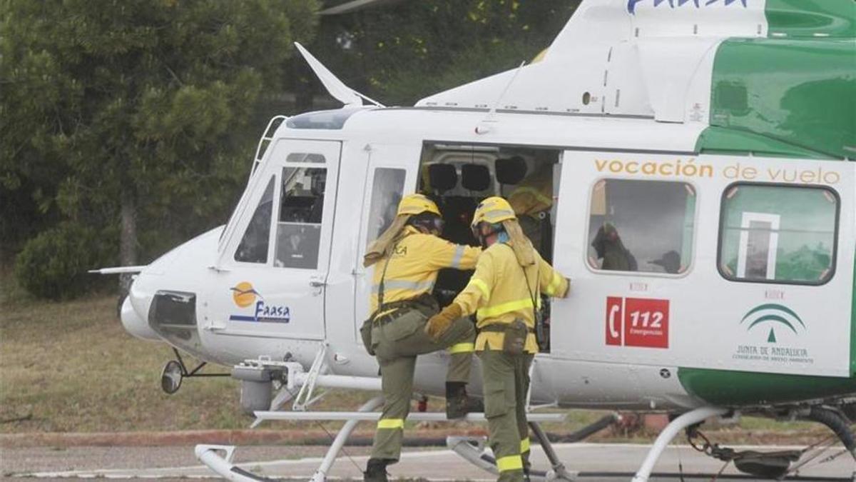 Dos bomberos suben a un helicóptero del Infoca.