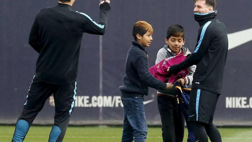 Messi firma autógrafos a dos aficionados que se colaron ayer en el entrenamiento. // A. Gea