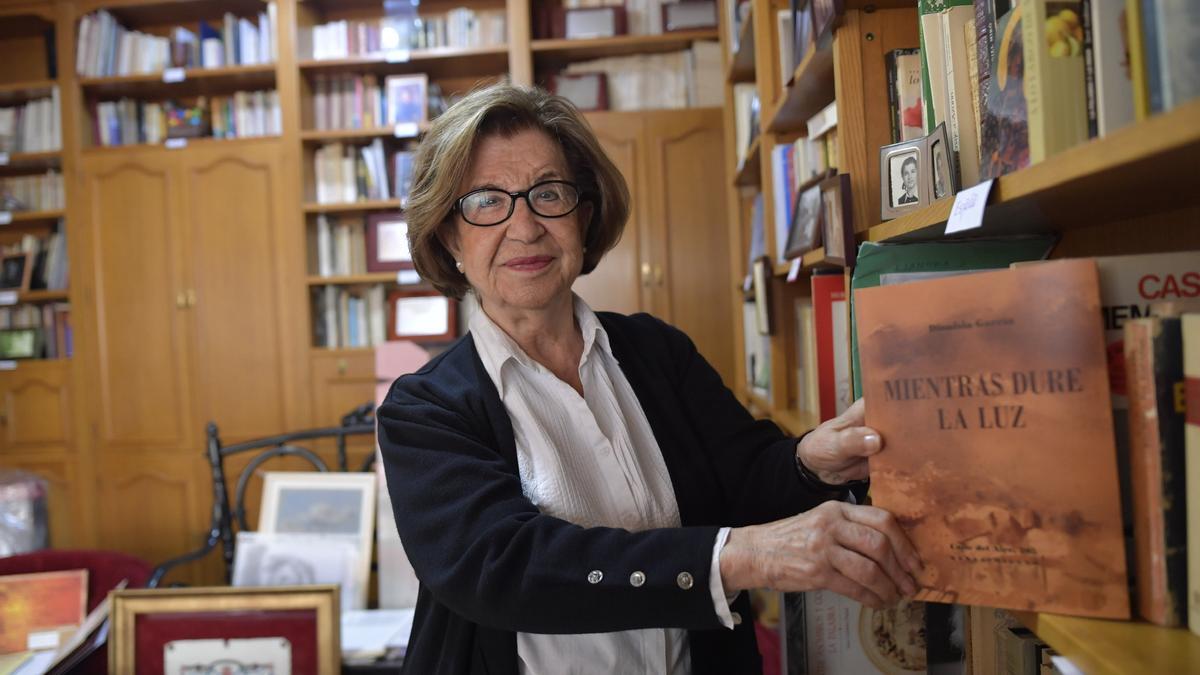 Dionisia García muestra su último poemario en la estantería de su librería.