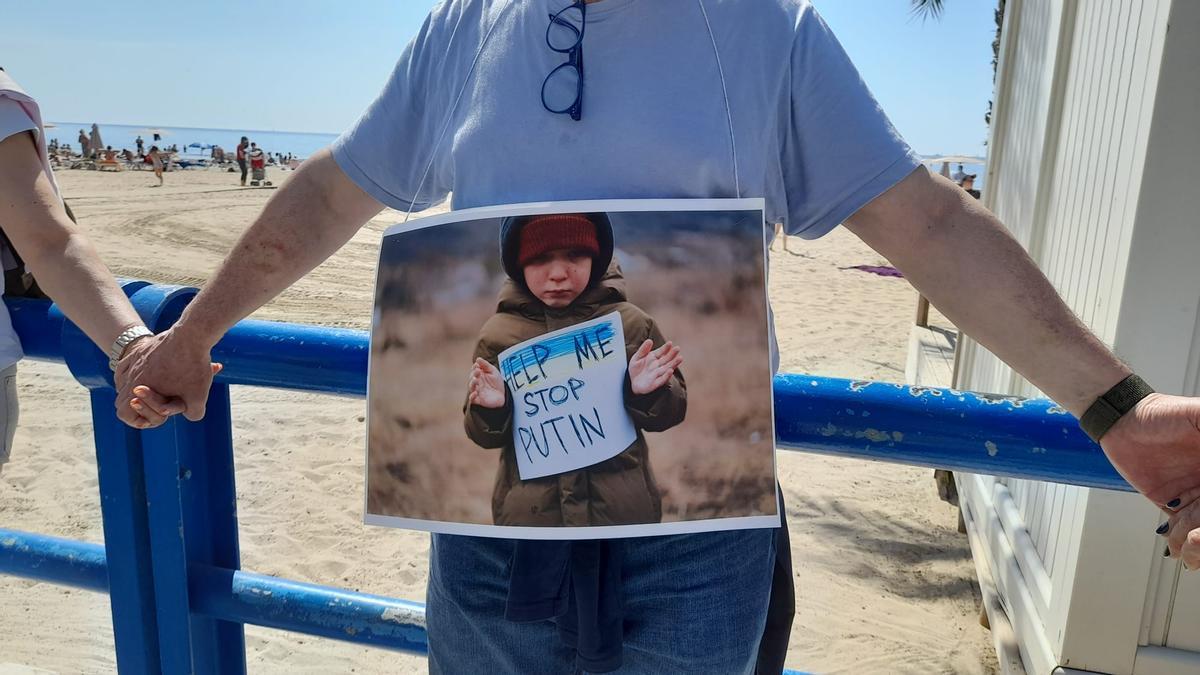 Un manifestante muestra una fotografía en la que un niño protesta contra Putin, en El Postiguet.