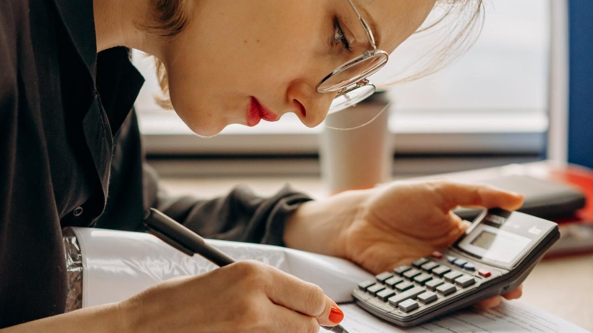 Una mujer realiza cuentas con una calculadora y un boli