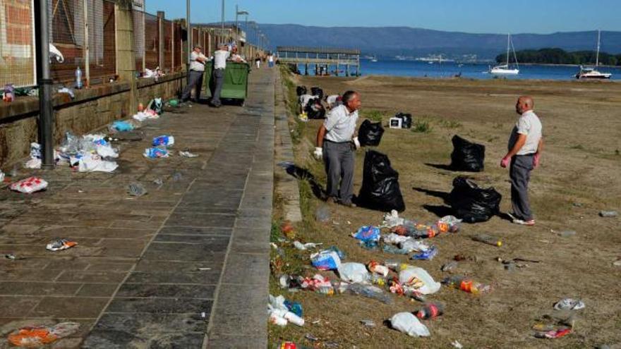 Operarios municipales limpiando la basura generada tras el &quot;botellón&quot; de la playa previo a la Festa da Auga.  // Iñaki Abella