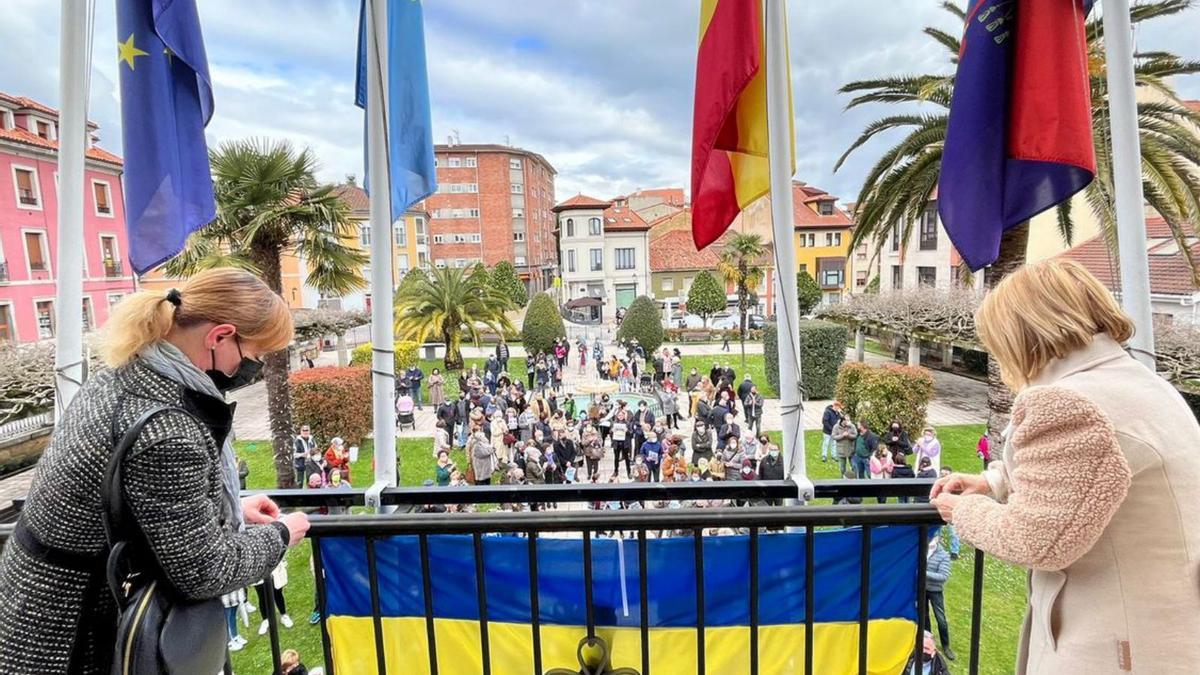 Tania Popovska y Amparo Antuña cuelgan la bandera de Ucrania en el balcón del Ayuntamiento de Noreña. | Inés Gago