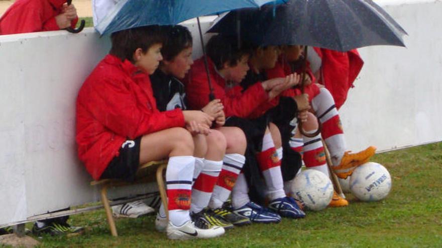 Unos niños de l&#039;Olleria protegiéndose de la lluvia con paraguas.