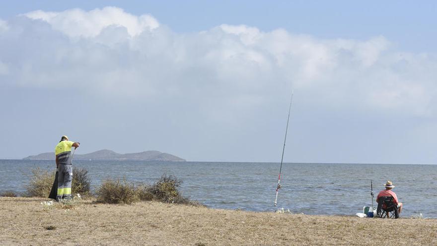 Un pescador (d) y un miembro del las brigadas de limpieza del Mar Menor, ante el agua