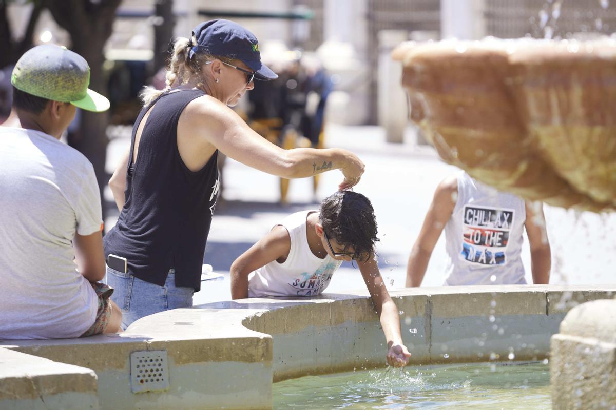 Un niño se refresca en una fuente en Sevilla.