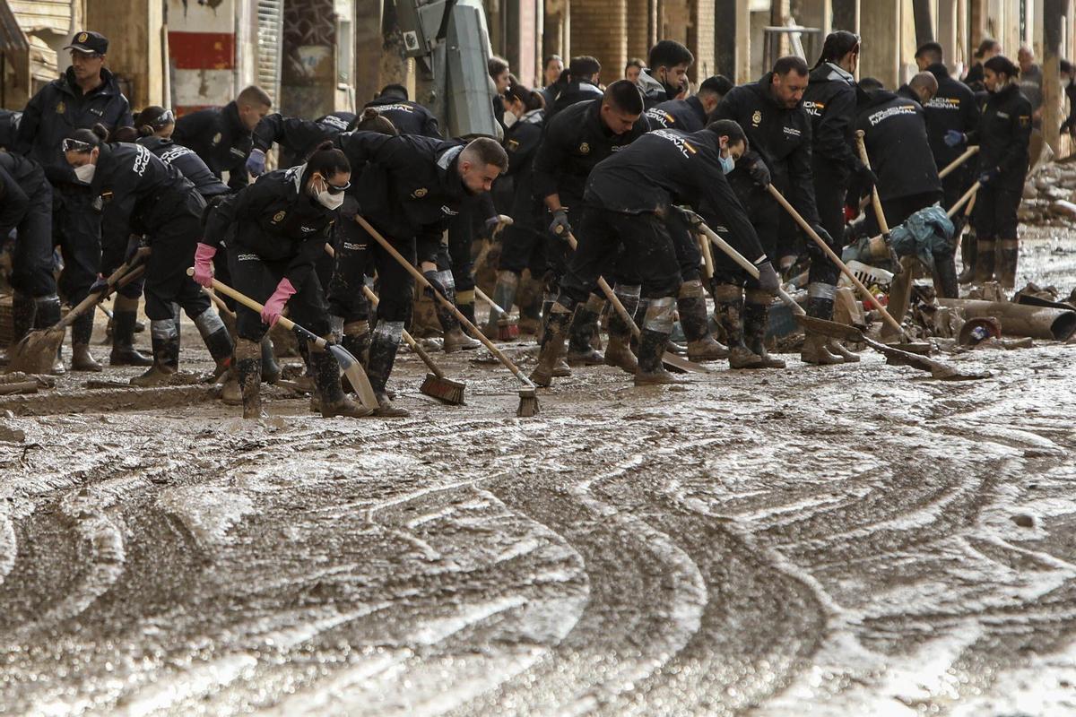 Policías Nacionales sacando el barro de las calles de Parque Alcosa.