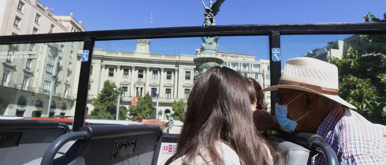 Pasajeros en el bus turístico de Zaragoza, ayer pasando por la plaza España.   | ANDREEA VORNICU