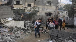 Niños palestinos en Gaza junto a los escombros de un edificio bombardeado