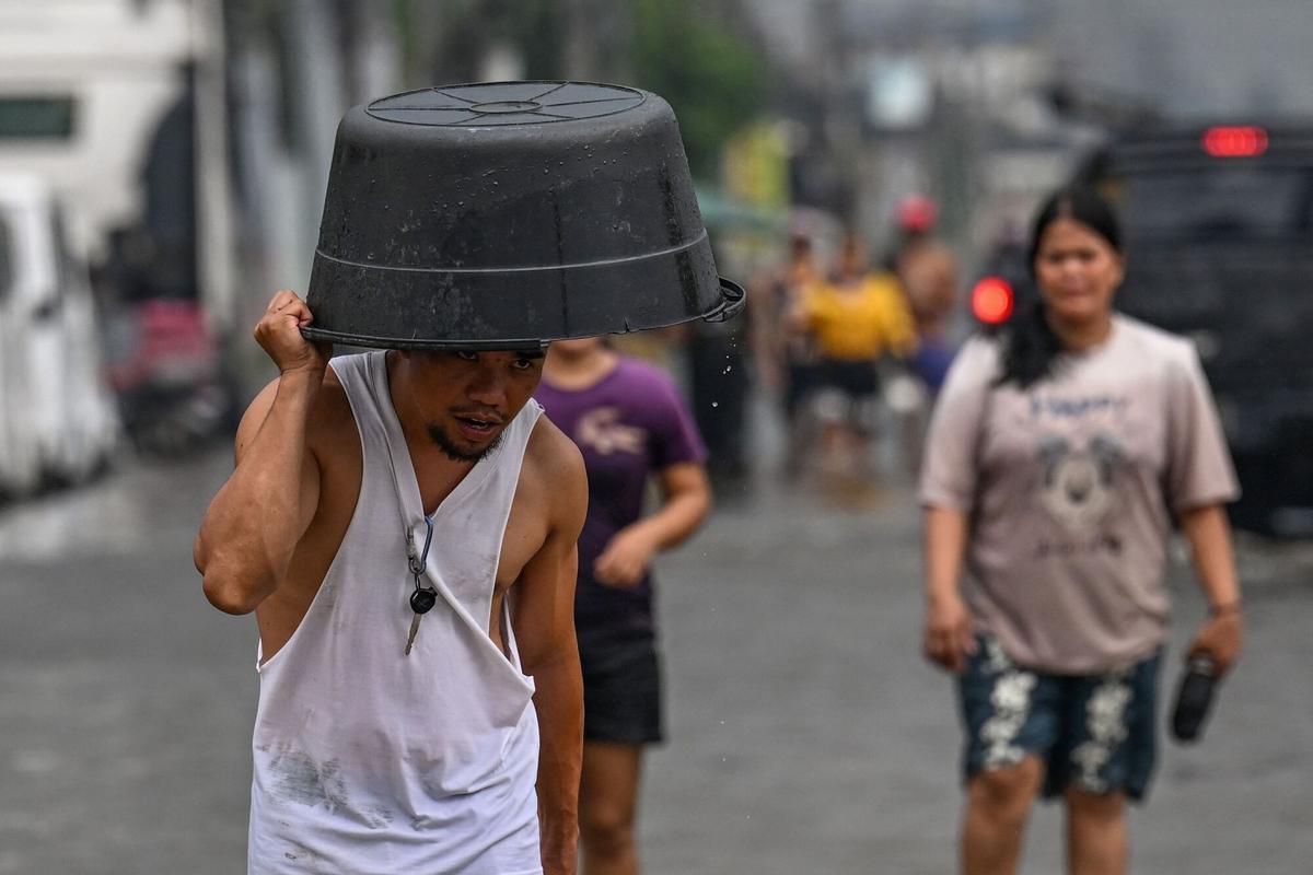 La gente camina a través de una calle inundada después de las fuertes lluvias traídas por el monzón del suroeste en Pampanga el 31 de agosto de 2026. (Foto de Jam STA ROSA / AFP)