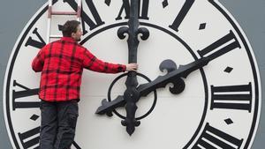 Un operario cambia las manecillas del reloj de una iglesia de Dresde. / AFP