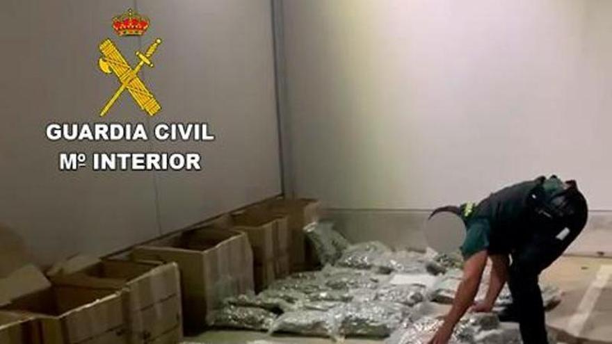 Un agente de la Guardia Civil, con las bolsas de marihuana interceptadas.