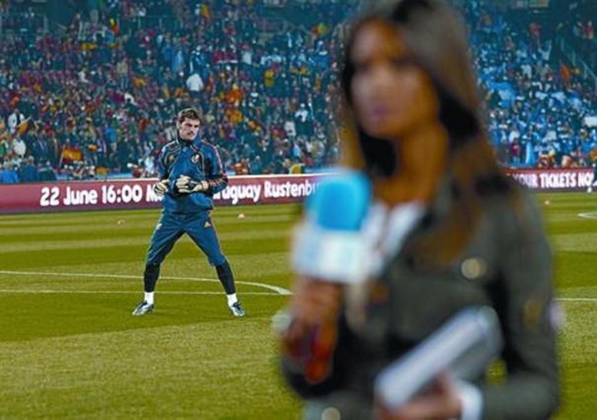 Iker Casillas s’escalfa moments abans del partit d’ahir mentre Sara Carbonero informa per a Tele 5.