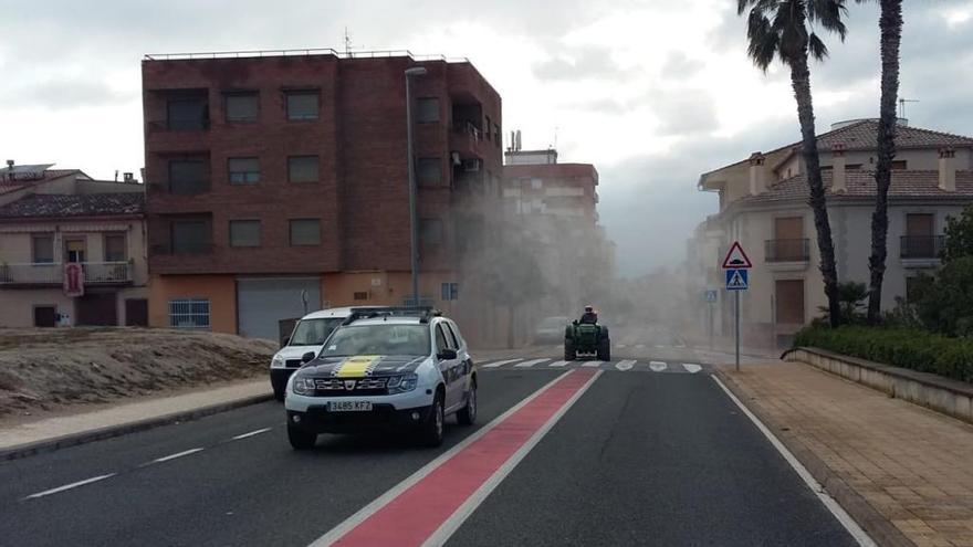 Un tractor desinfecta las calles de Aielo de Malferit, precedido por la policía