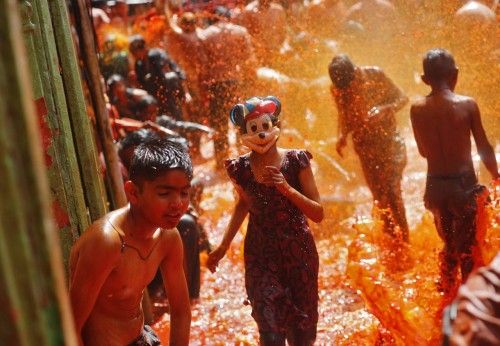 A girl wearing a mask runs as boys splash coloured water on her during "Huranga" at Dauji temple, near the northern Indian city of Mathura