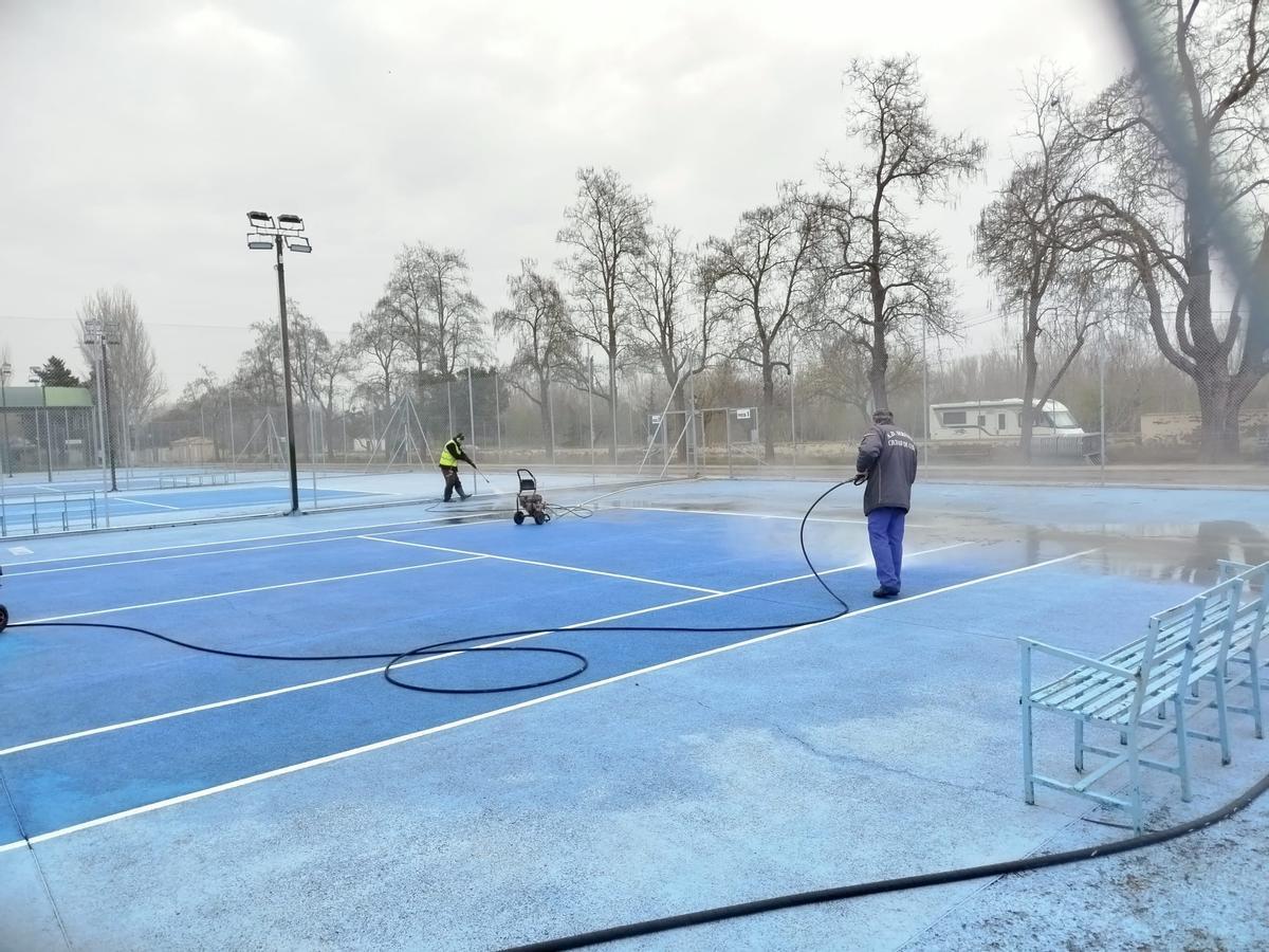 Trabajadores municipales realizan tareas de limpieza en pistas deportivas.