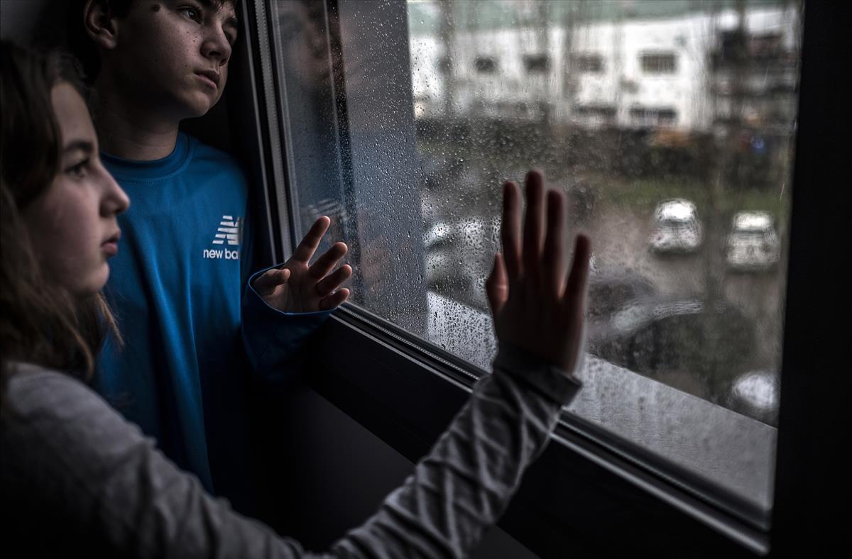 Día de lluvia en la tercera semana de confinamiento domiciliario y estado de alarma. En la foto, Emma y Bruno, primos que se encuentran confinados juntos a causa de que la madre de él trabaja como médico en la UCI del Hospital Vall d’Hebron en Barcelona y ha debido tomar la decisión de confinar a su hijo en casa de unos familiares. 