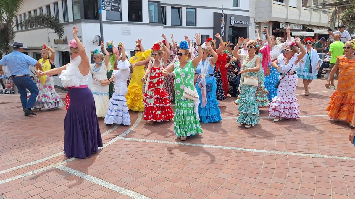 Algunas participantes de la Feria de Abril del Real Club Victoria bailan en el paseo de Las Canteras.