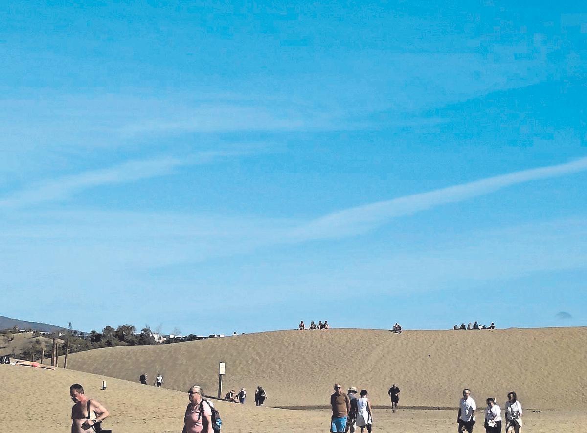 Turistas camino o de vuelta  de las Dunas de Maspalomas. Arriba, grupos de adolescentes.