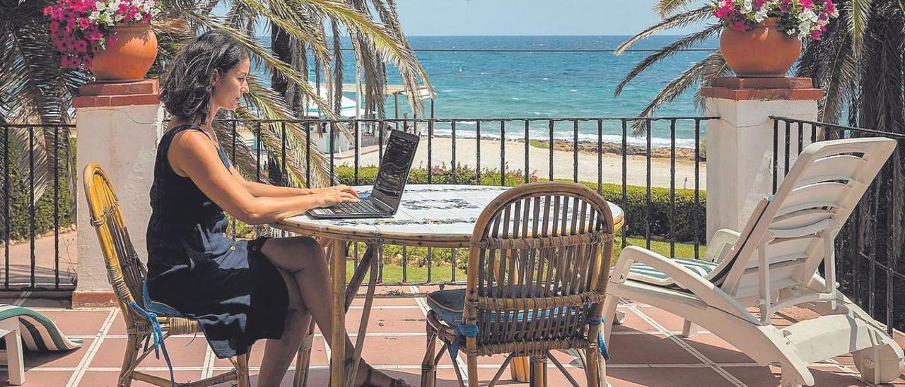 Una mujer teletrabaja en la playa de Jávea.