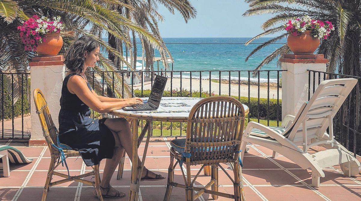 Una mujer teletrabaja en la playa de Jávea.