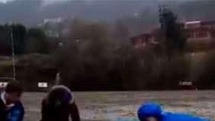 Cuatro voluntarios, achicando el agua del campo de rugby del Naranco ayer por la tarde.