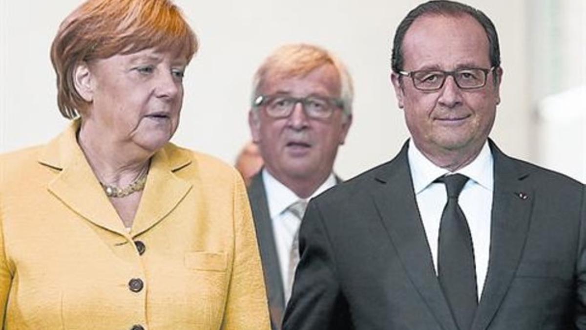 Merkel y Hollande, con Juncker detrás, ayer, en Berlín.