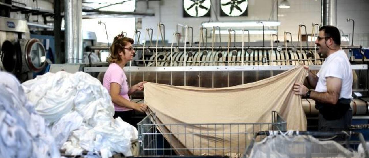 Dos usuarios del centro de empleo del Doble Amor, en la lavandería industrial, en foto de archivo.