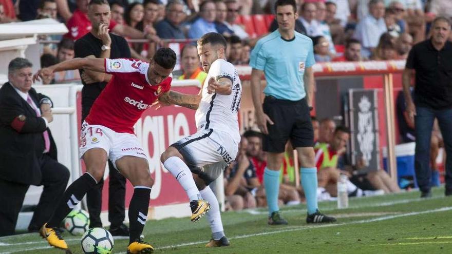 Rubén García presiona a Maikel Mesa con el banquillo del Sporting al fondo.