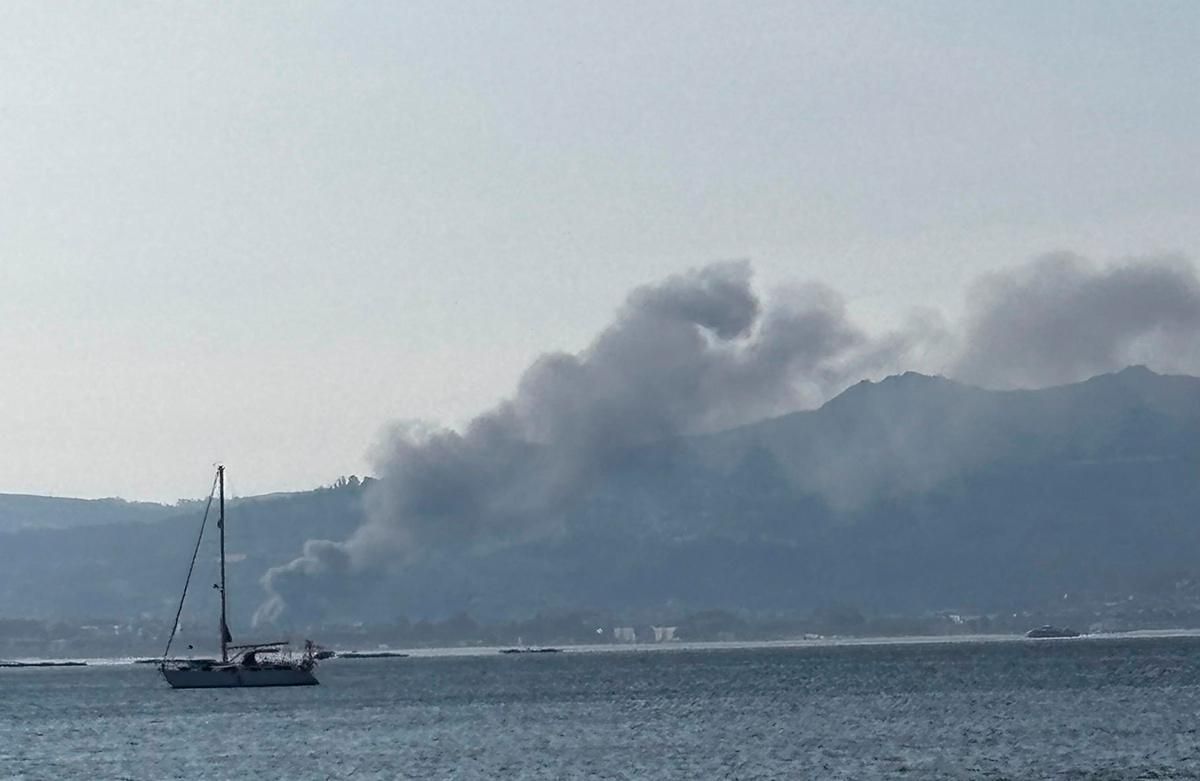 Columna de humo del incendio en el polígono de Caramuxo visto desde el otro lado de la ría.