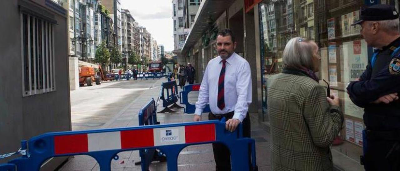 Iván Moral, uno de los trabajadores de la agencia de viajes, ayer, junto a la valla, y un policía.