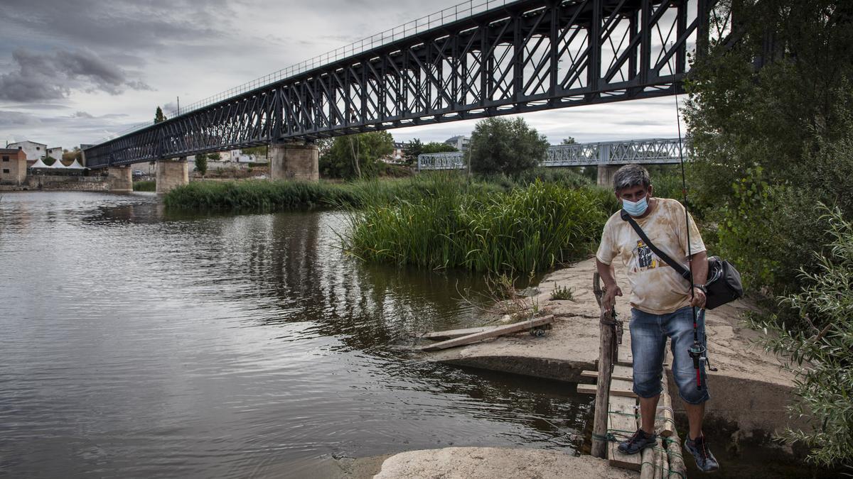 Un pescador junto a las antiguas vías del tren Ruta de la Plata sobre el río Duero.