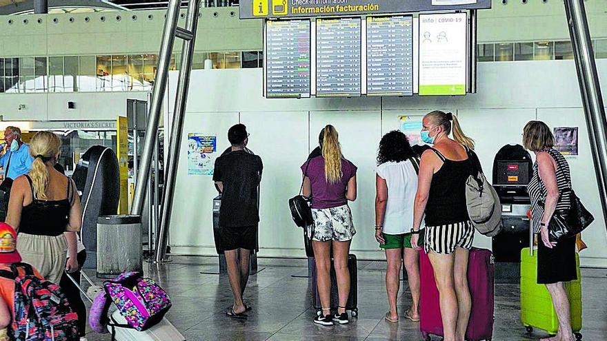 Pasajeros consultando ayer los horarios de sus vuelos en la terminal de salidas del aeropuerto de Alicante-Elche.