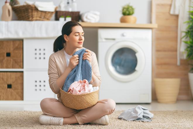 Mujer oliendo ropa lavadora