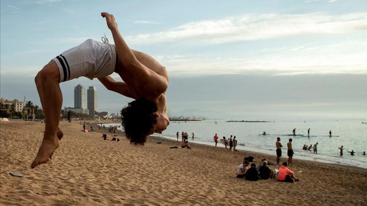 Unos jóvenes practican deporte en la playa de la Barceloneta.