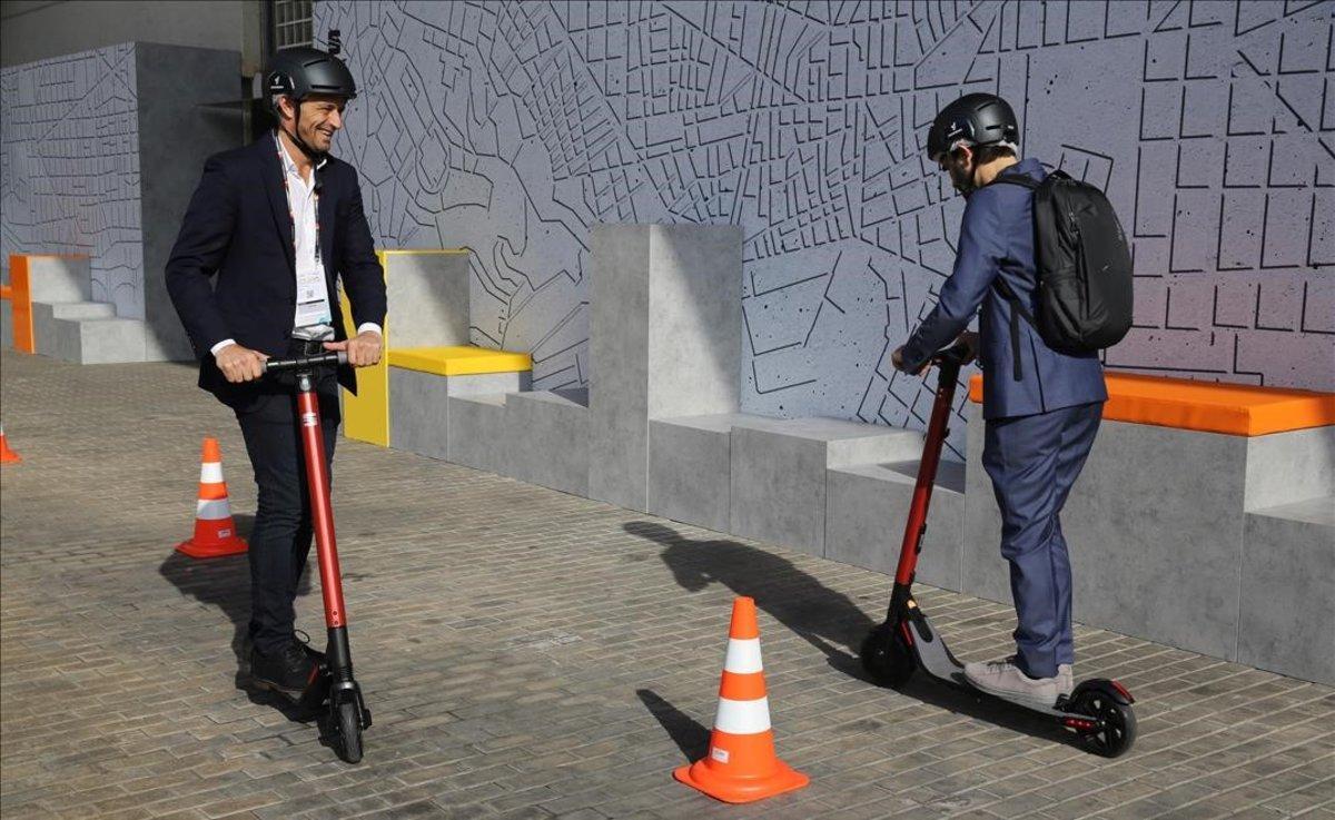 Dos personas prueban los patinetes eléctricos de Seat en la Smart City Expo de Barcelona.
