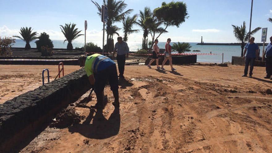 Un trabajador del Ayuntamiento de Teguise recoge lodo del acceso peatonal a la playa de Las Cucharas