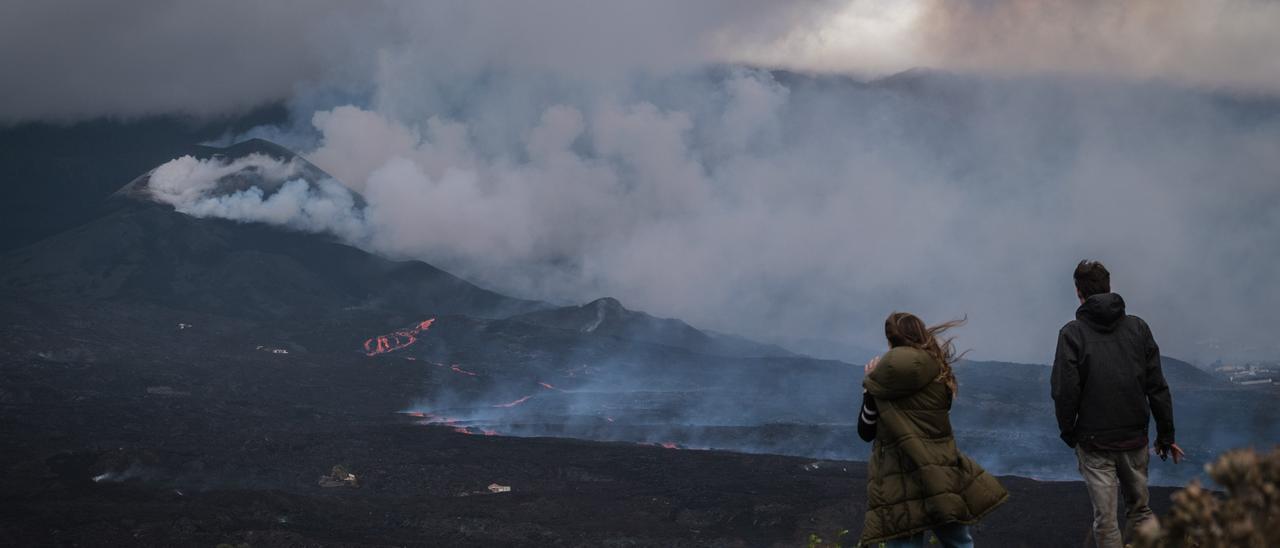 Dos personas observan las coladas del volcán de La Palma.