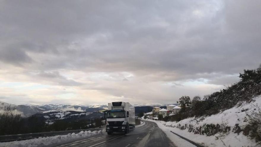 Un camión circula por una carretera con presencia de nieve en las cunetas.