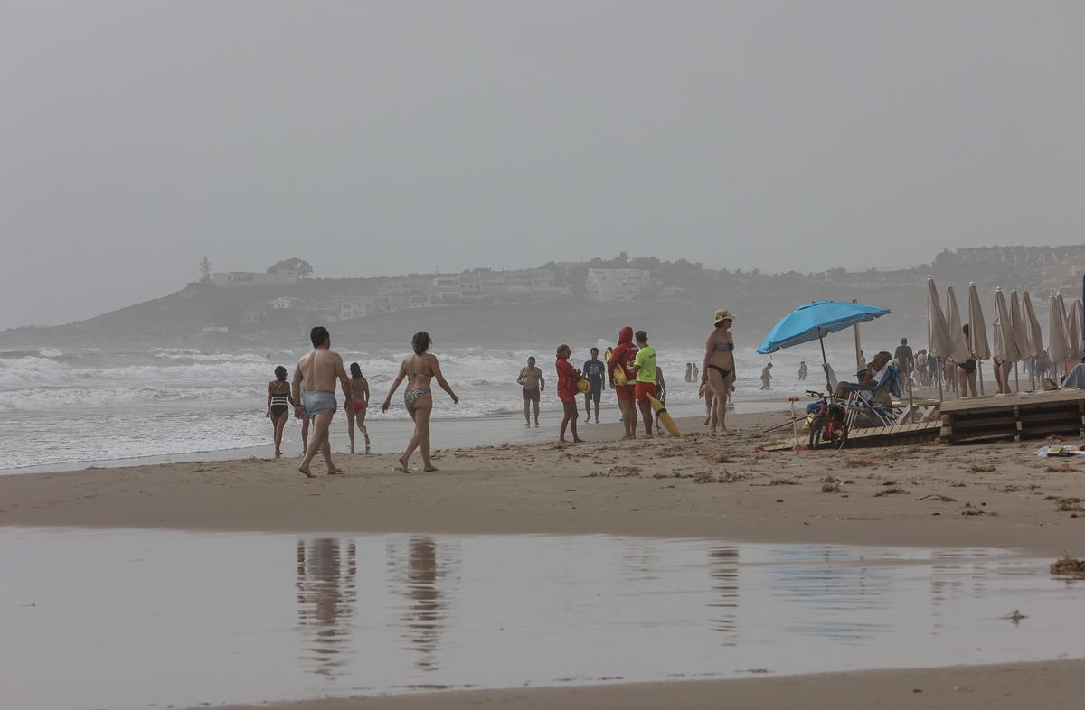 Bañistas paseando por la Playa de San Juan este lunes a pesar del tiempo.