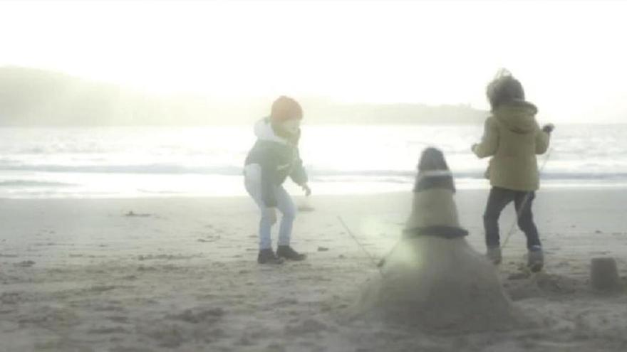 Captura del vídeo promocional de Nigrán en el que dos niños moldean un muñeco &quot;de nieve&quot; en la playa. // Samaín Producións