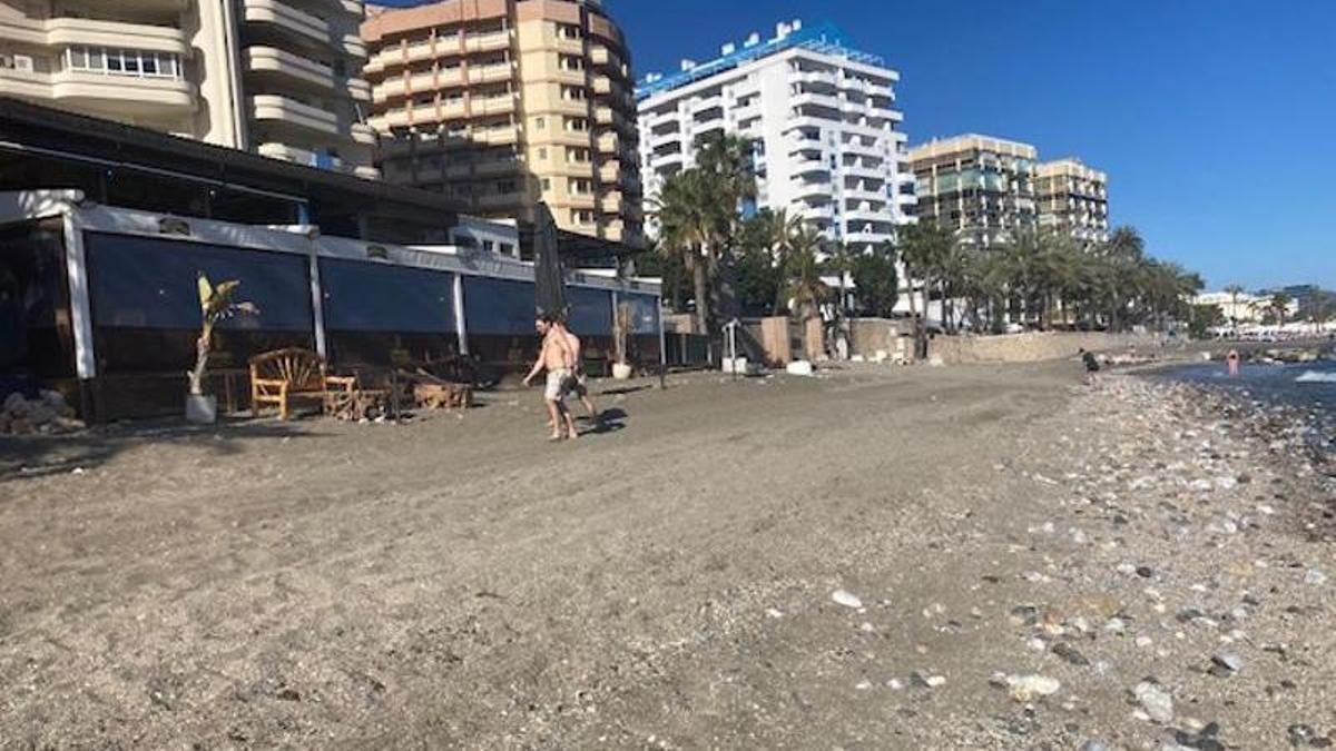 Turistas pasan por delante de un establecimiento de playa en Marbella, a escasa distancia de la orilla.