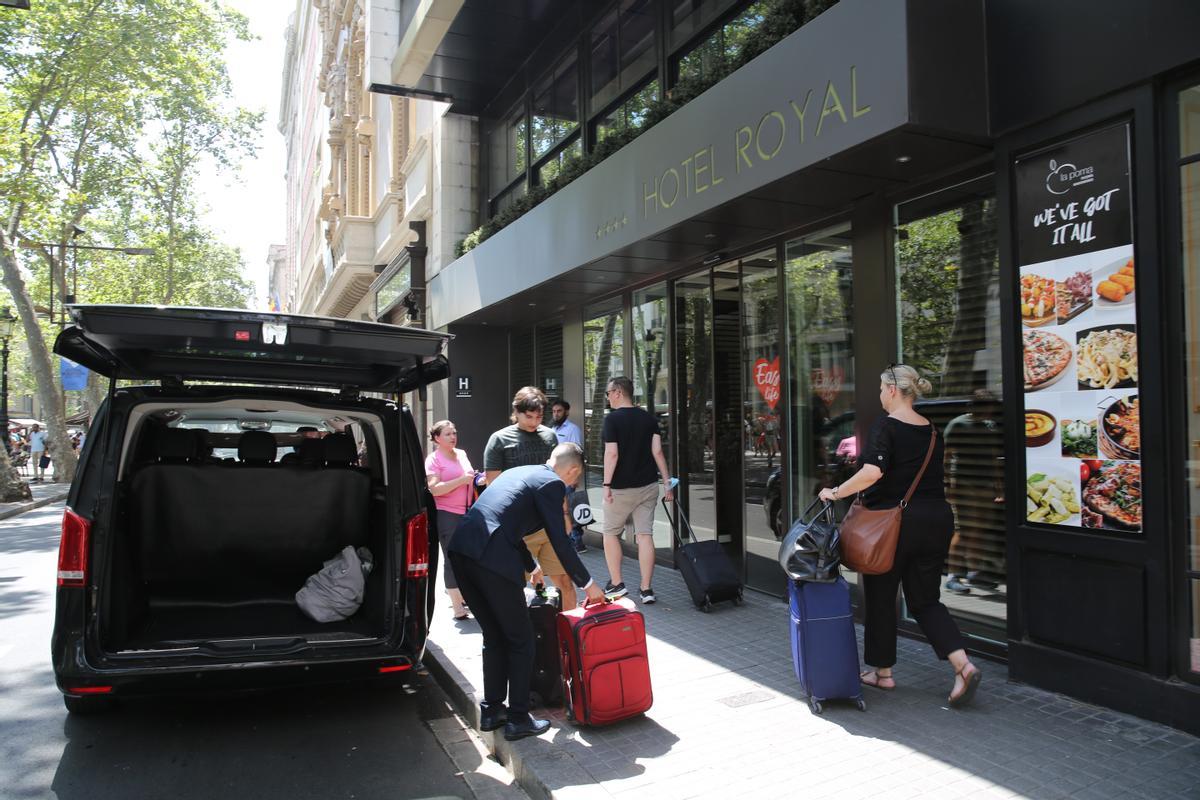 El conductor de una VTC descarga las maletas de unos turistas dispuestos a hospedarse en uno de los hoteles de la Rambla